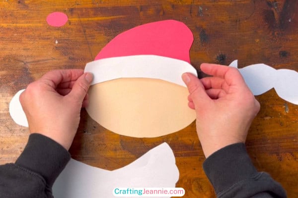 step 2 of santa craft glue white rim onto the red hat